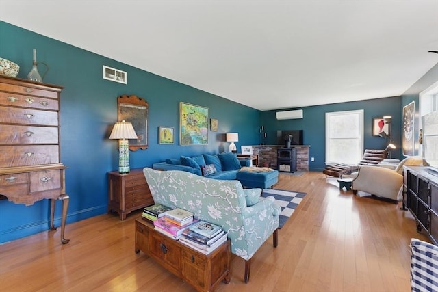 living room with visible vents, a wall mounted air conditioner, and wood finished floors