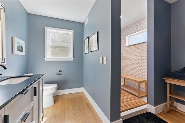 bathroom featuring toilet, baseboards, wood finished floors, and vanity