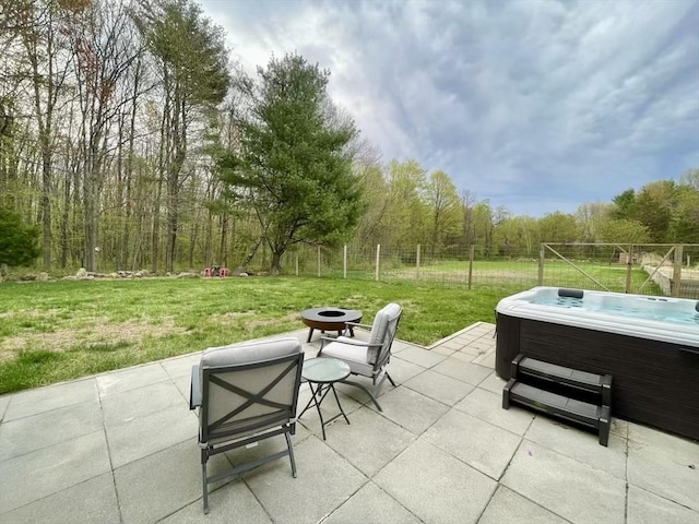 view of patio / terrace with fence, a hot tub, and an outdoor fire pit