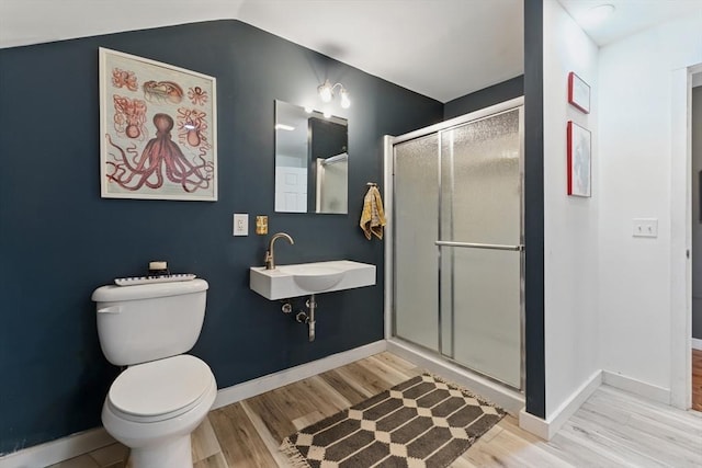 full bath featuring toilet, a shower stall, a sink, and wood finished floors