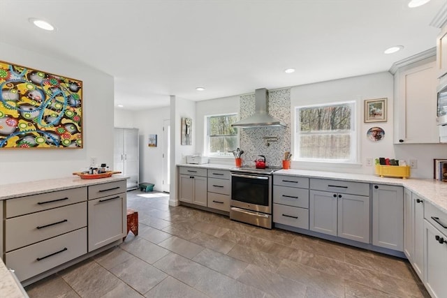 kitchen with stainless steel range with electric stovetop, wall chimney exhaust hood, recessed lighting, backsplash, and gray cabinetry