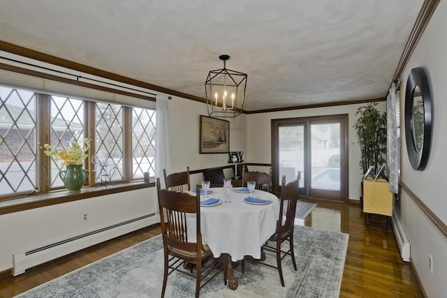dining space featuring a chandelier, ornamental molding, baseboard heating, and wood finished floors