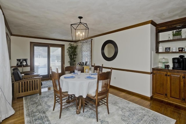 dining area with an inviting chandelier, crown molding, and wood finished floors
