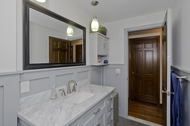 bathroom with vanity, wood finished floors, a wainscoted wall, and a decorative wall
