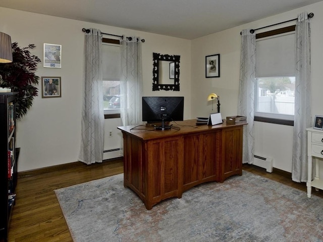 home office featuring baseboard heating, baseboards, and wood finished floors