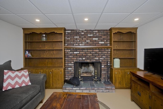 living room featuring recessed lighting, a paneled ceiling, and a fireplace