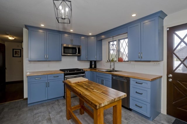 kitchen with backsplash, blue cabinets, a sink, wood counters, and stainless steel appliances
