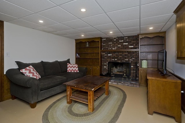 living room with recessed lighting, a paneled ceiling, built in shelves, and a fireplace