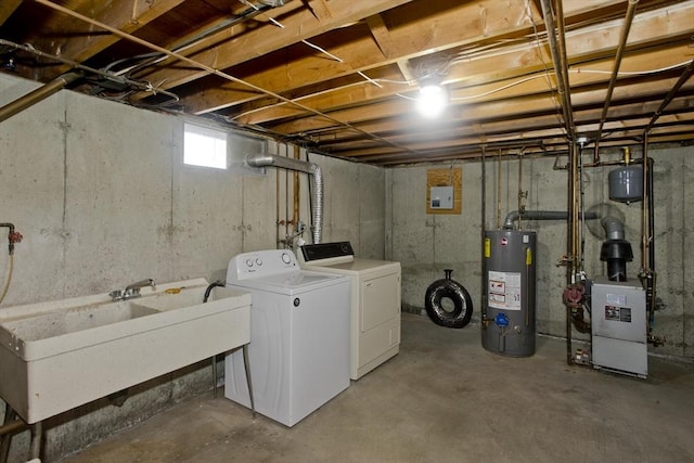 washroom featuring washing machine and clothes dryer, laundry area, a sink, and water heater