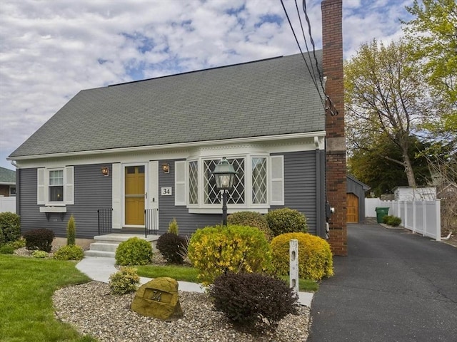 new england style home featuring fence, an outbuilding, and a chimney