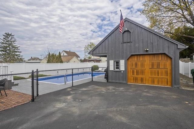 detached garage with a fenced in pool and fence