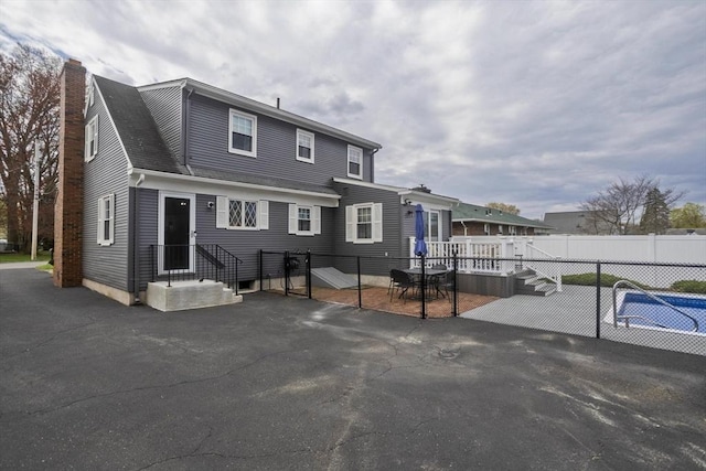view of front of house featuring fence, a patio, and a chimney