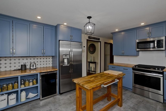 kitchen with appliances with stainless steel finishes, tasteful backsplash, wooden counters, wine cooler, and blue cabinets