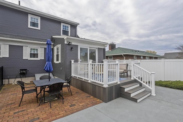 rear view of property featuring fence, outdoor dining space, a patio area, and a deck
