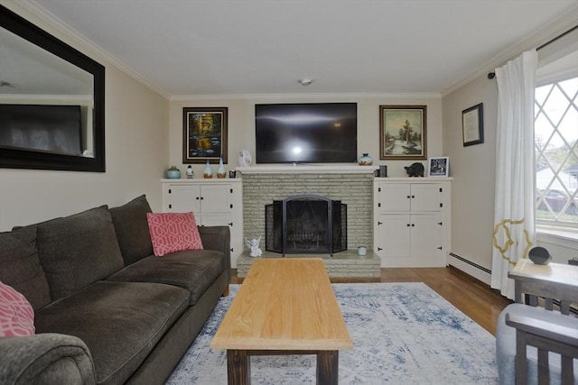 living area with a fireplace, wood finished floors, a wealth of natural light, a baseboard radiator, and ornamental molding