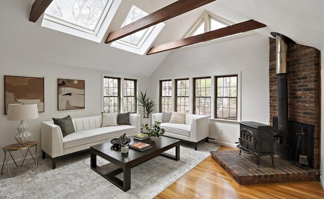 living area featuring a wood stove, high vaulted ceiling, wood finished floors, beamed ceiling, and a skylight