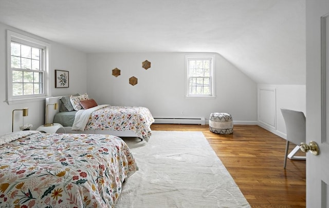 bedroom featuring multiple windows, wood finished floors, a baseboard radiator, and vaulted ceiling