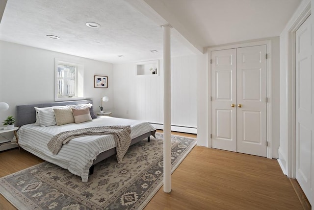 bedroom with wood finished floors and baseboard heating