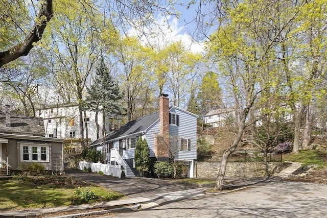 view of side of property with driveway, a chimney, and an attached garage