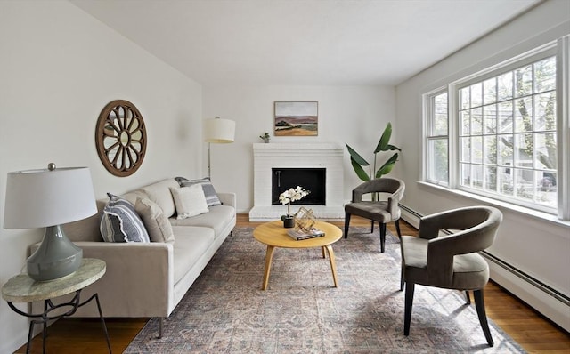 living room featuring plenty of natural light, a baseboard heating unit, and wood finished floors