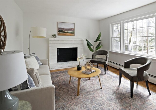 living room with wood finished floors, baseboard heating, a baseboard radiator, and a fireplace