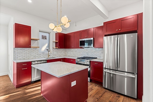 kitchen featuring appliances with stainless steel finishes, a kitchen island, sink, decorative light fixtures, and backsplash