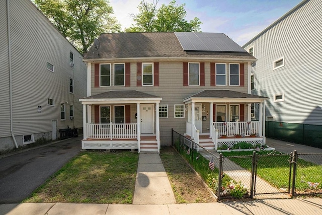 30 Balfour St, Boston, MA 02125 - view of front of home featuring covered porch, roof mounted solar panels, roof with shingles, and a fenced front yard