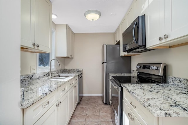 kitchen with light tile patterned floors, light stone countertops, baseboards, a sink, and appliances with stainless steel finishes