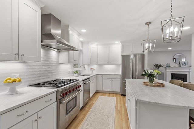 3 Misty Ln, Westford, MA 01886 - kitchen with high end appliances, wall chimney exhaust hood, a sink, a kitchen island, and light wood-type flooring