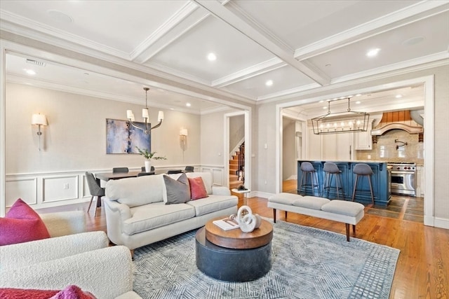 living room with ornamental molding, beam ceiling, and light wood-type flooring