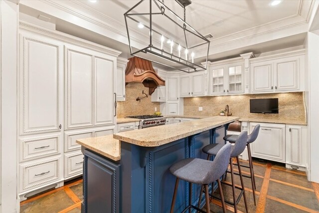 kitchen featuring white cabinetry, a kitchen bar, a kitchen island, and stainless steel stove