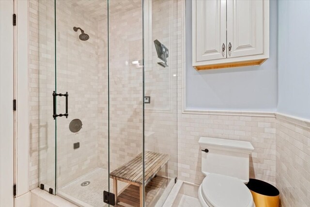 bathroom featuring tile walls, toilet, and an enclosed shower