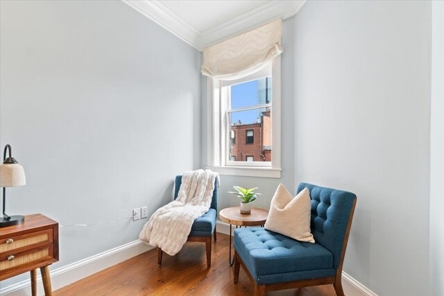 living area with crown molding and hardwood / wood-style flooring