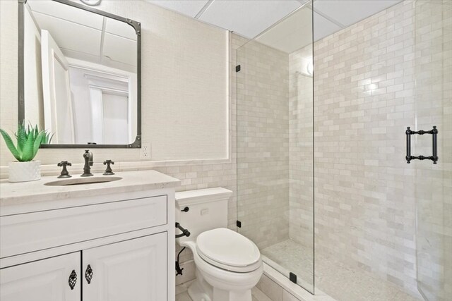 bathroom with tile walls, vanity, toilet, and walk in shower