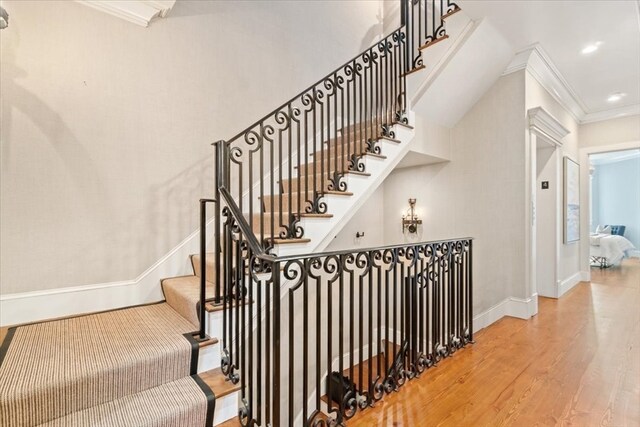 stairway with crown molding and hardwood / wood-style floors