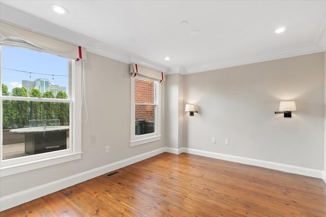 spare room with crown molding, hardwood / wood-style flooring, and plenty of natural light