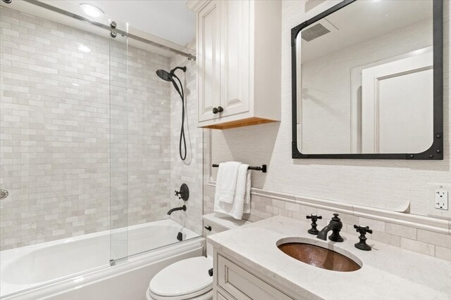 full bathroom featuring vanity, toilet, shower / bath combination with glass door, and backsplash