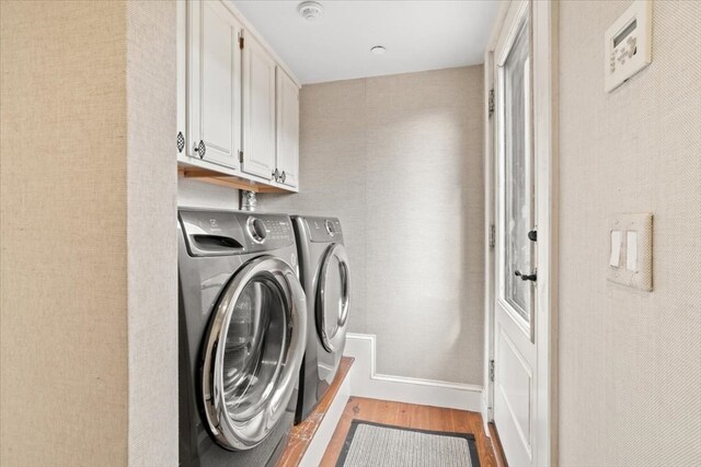 washroom featuring hardwood / wood-style flooring, cabinets, and washer and clothes dryer