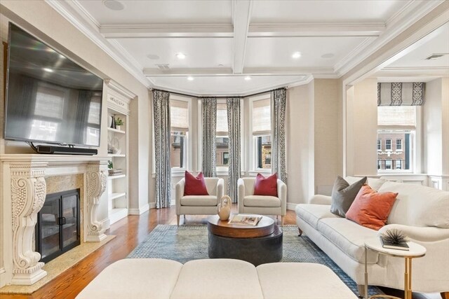 living room with beam ceiling, a premium fireplace, a wealth of natural light, and light wood-type flooring