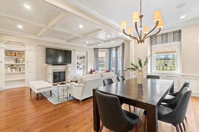 dining area featuring light hardwood / wood-style floors, coffered ceiling, ornamental molding, and plenty of natural light