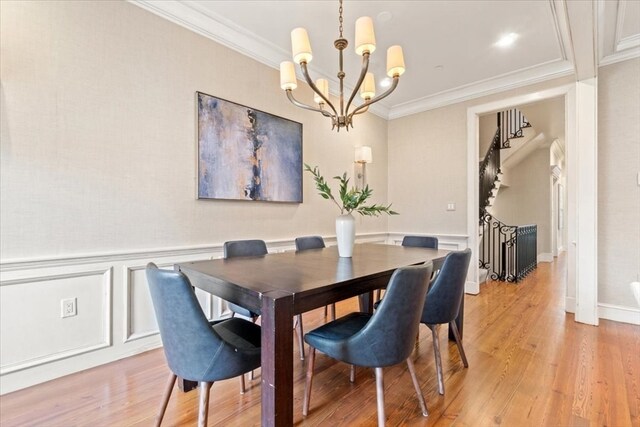 dining room featuring an inviting chandelier, light hardwood / wood-style flooring, and ornamental molding