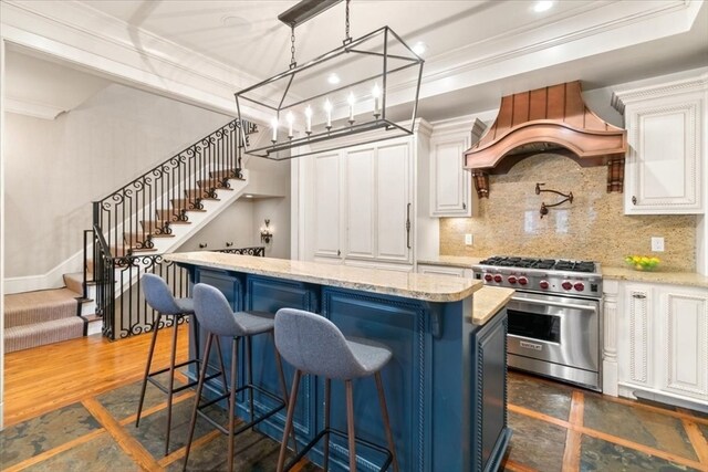 kitchen with luxury stove, white cabinets, custom range hood, and a kitchen island