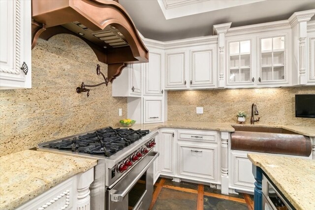 kitchen with high end stove, white cabinetry, and light stone countertops