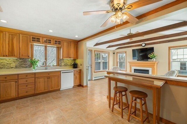 kitchen with a sink, brown cabinetry, baseboard heating, dishwasher, and tasteful backsplash