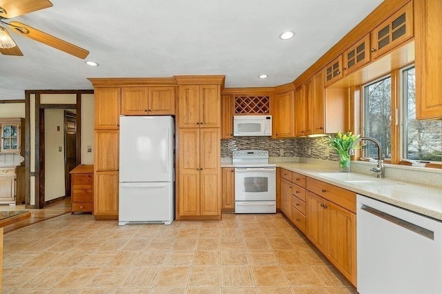 kitchen with a sink, white appliances, ceiling fan, decorative backsplash, and light countertops