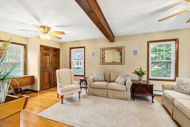 living area with light wood-type flooring, beamed ceiling, a ceiling fan, and baseboard heating
