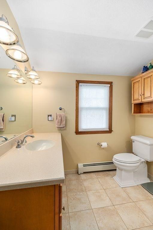 bathroom with toilet, vanity, visible vents, tile patterned floors, and baseboard heating
