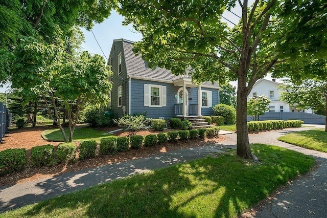 view of front of property featuring fence, a shingled roof, and a front lawn