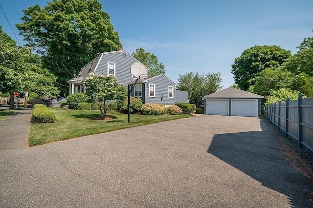 view of side of home with a garage, fence, a lawn, an outdoor structure, and a gambrel roof