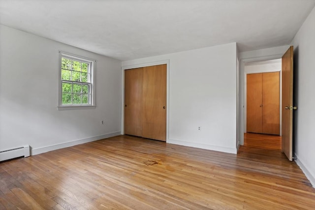 30 Juniper Cir, Concord, MA 01742 - unfurnished bedroom with light wood finished floors, baseboards, a closet, and a baseboard radiator
